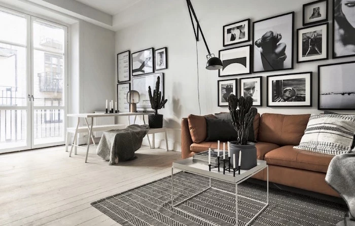 brown leather sofa black and white framed photos hanging on white wall scandinavian interior design black and white rug on wooden floor