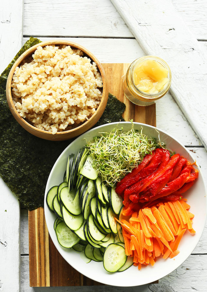 brown rice in wooden bowl best vegan appetizers plate full of roasted peppers cucumber slices carrots sprouts