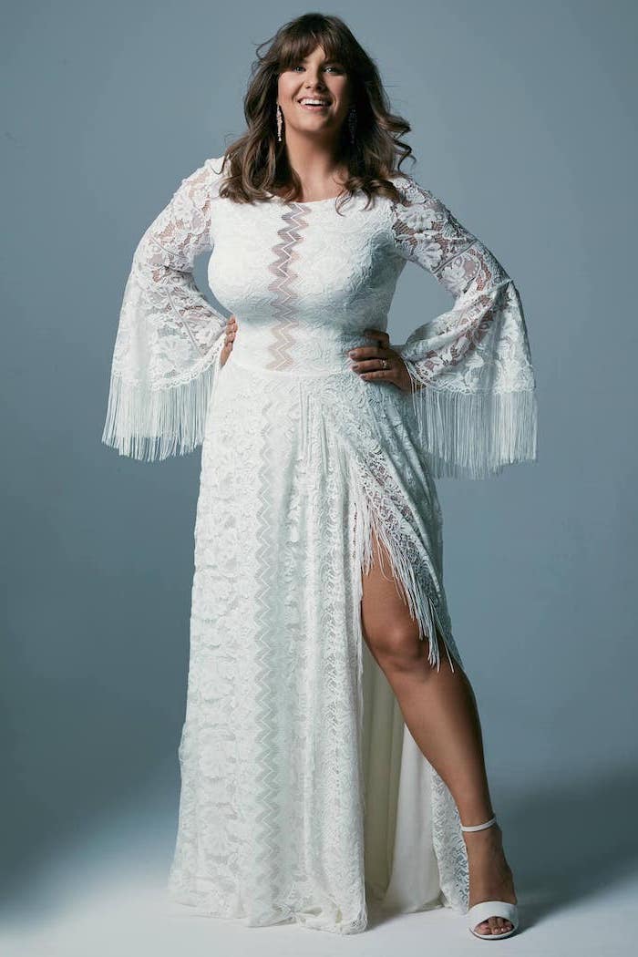 brunette woman with bangs wearing dress made of lace with fringe on the bottom of the sleeves bohemian style wedding dresses white sandals