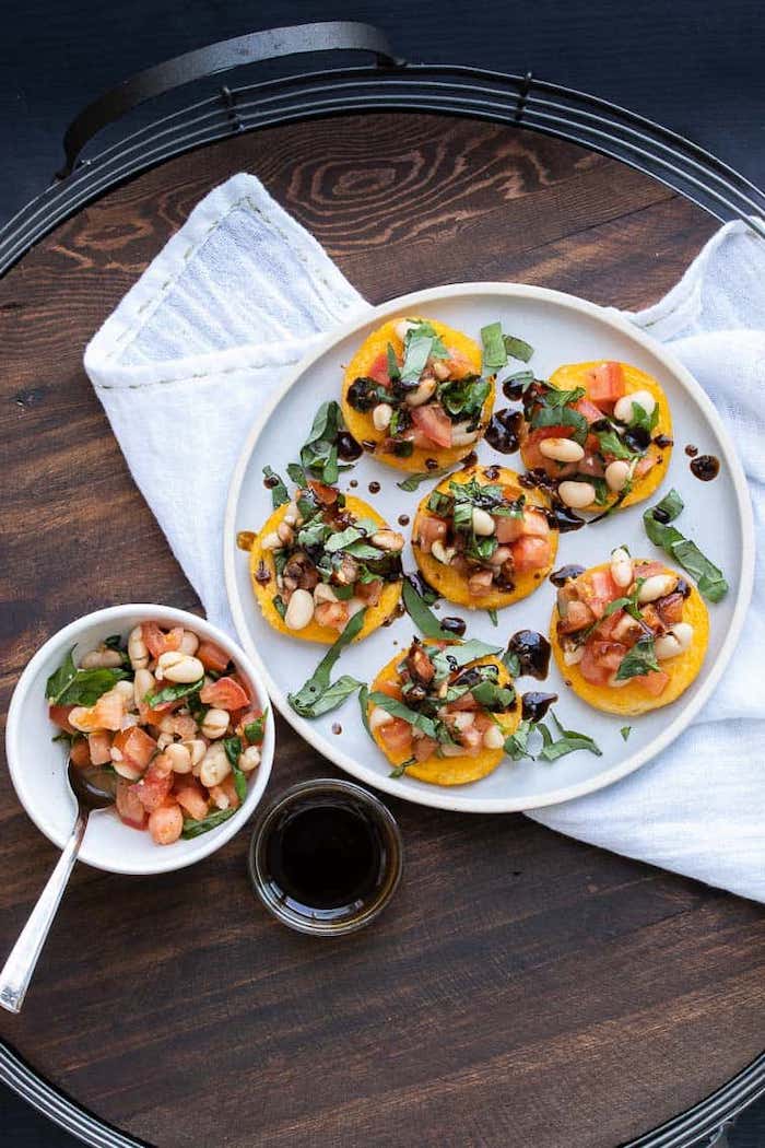 bruschetta with beans tomatoes basil leaves in white plate vegan appetizer recipes placed on wooden surface