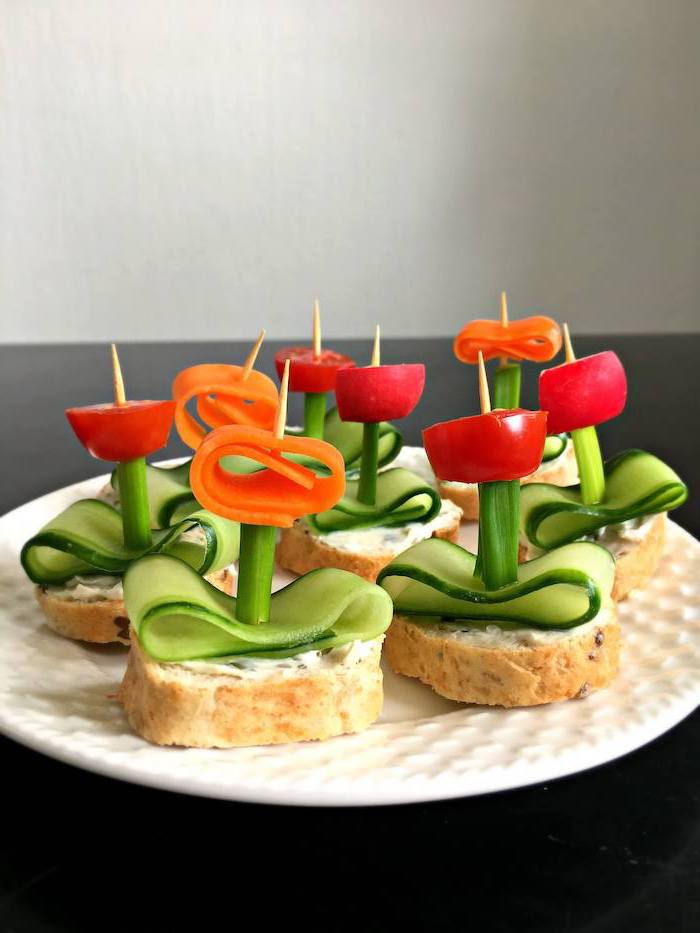 bruschetta with cream cheese cucumber slices tomatoes carrots arranged on white plate vegan party food