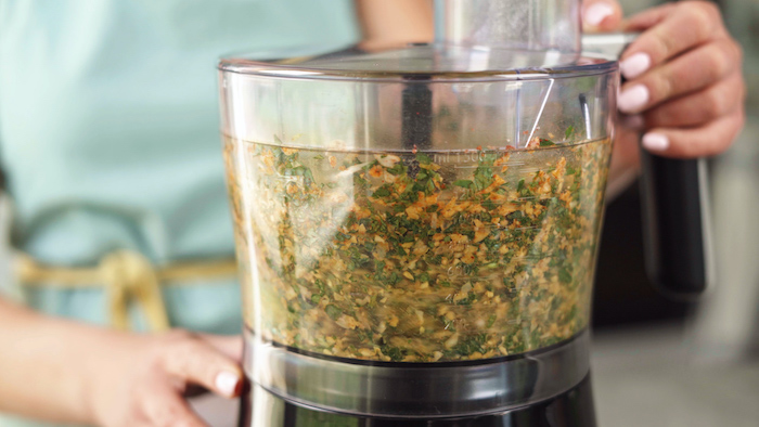 chickpeas herbs garlic olive oil blended in a blender vegan finger food by woman wearing blue apron