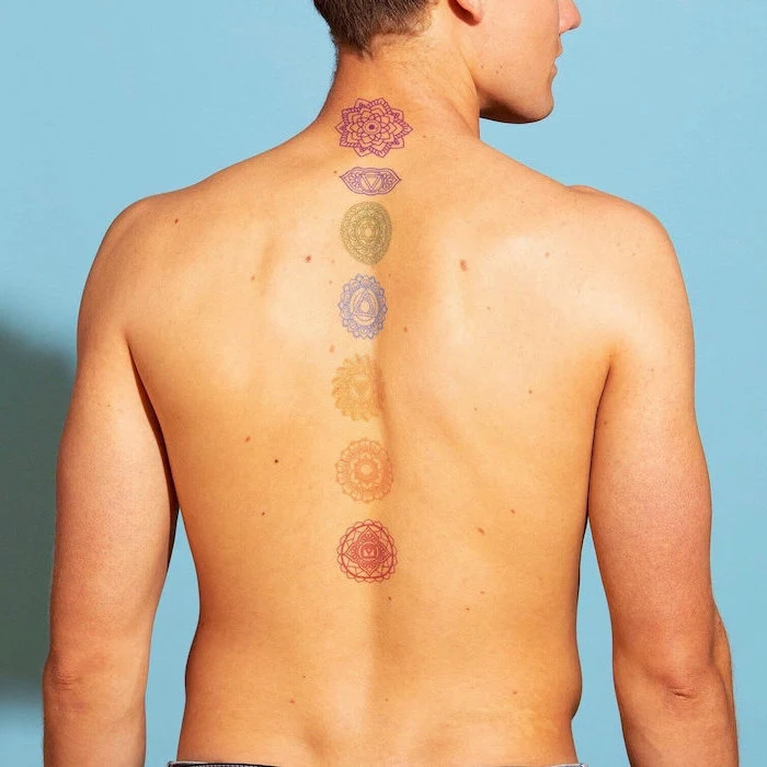 colorful chakras back tattoo down the spine on man with blonde hair tattoos with deep meaning blue background
