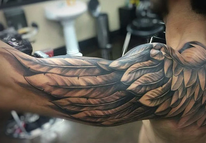 eagle wings upper arm sleeve tattoo starting from the back simple tattoos for men blurred background