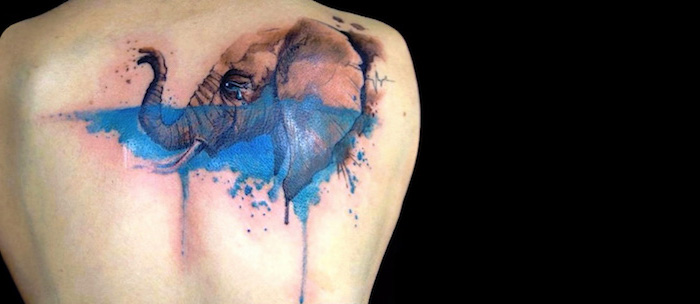 elephant hand watercolor tattoo in blue on the back meaningful tattoos for men black background