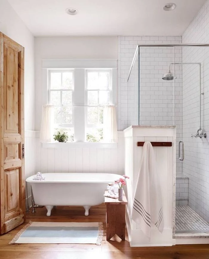 farmhouse bathroom ideas white subway tiles in the shower separate bath on wooden floor small rug next to it