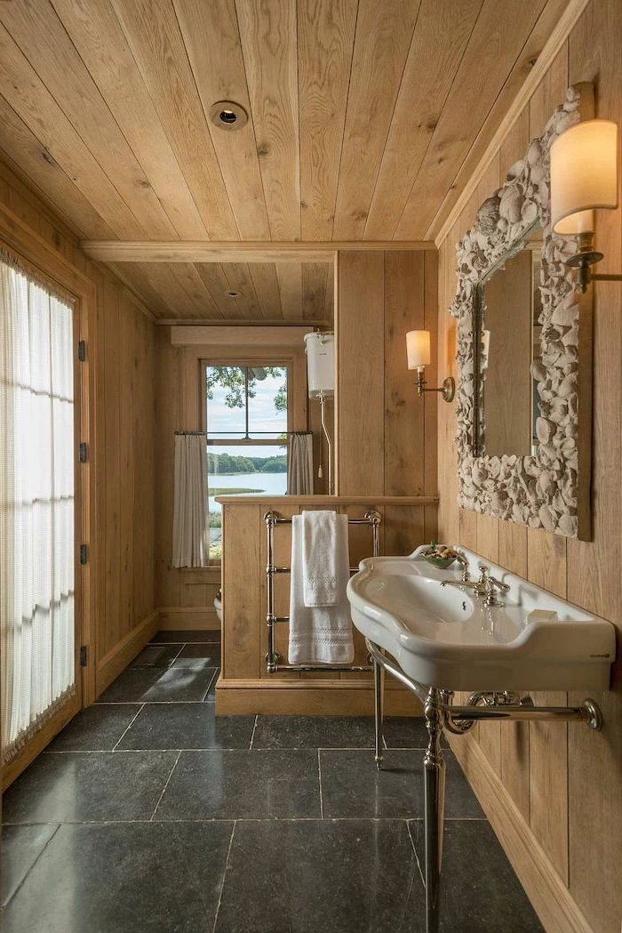 farmhouse bathroom shelves wooden shiplap ceiling and walls black tiles on the floor mirror above the sink with seashells covered mirror