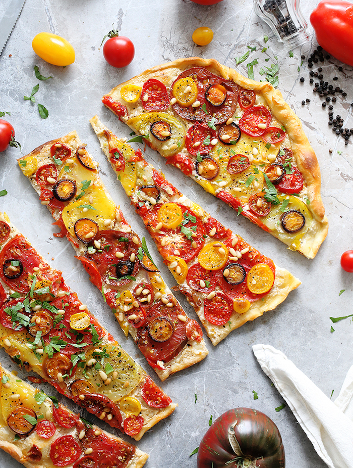 flatbread baked with different kinds of tomatoes pine nuts chopped parsley cut into pieces vegan finger food granite surface