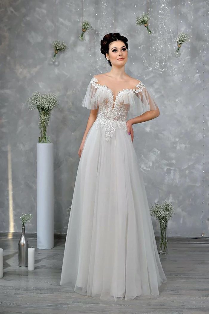 flowy wedding dress worn by woman with black hair in high updo bottom of the dress made of tulle