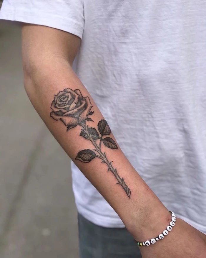 forearm tattoos for men rose with thorns tattooed on man wearing white t shirt jeans no stress bracelet
