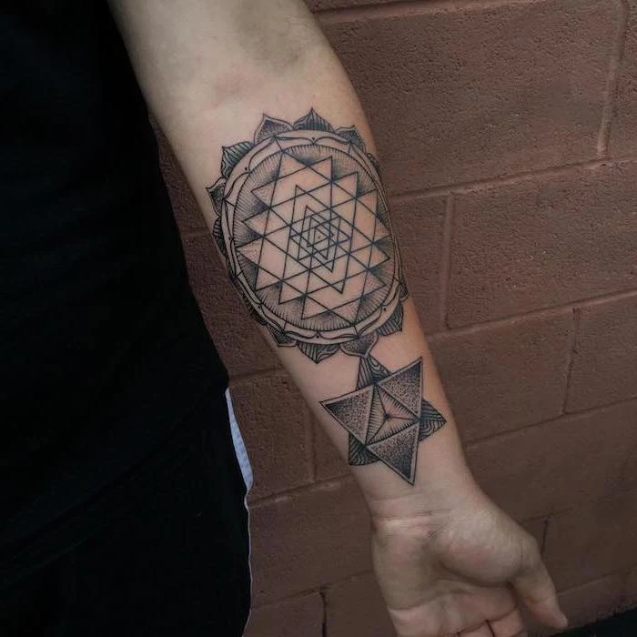 geometric tattoo on the forearm of man wearing black pants and top meaningful tattoo ideas for women