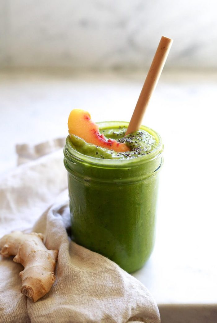 glass filled with green smoothie garnished with chia seeds peach slice best detox cleanse for weight loss ginger next to the glass