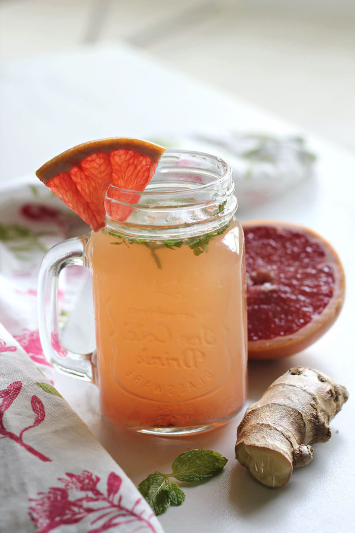 grapefruit juice with ginger and fresh mint leaves poured inside glass how to detox your body placed on white surface