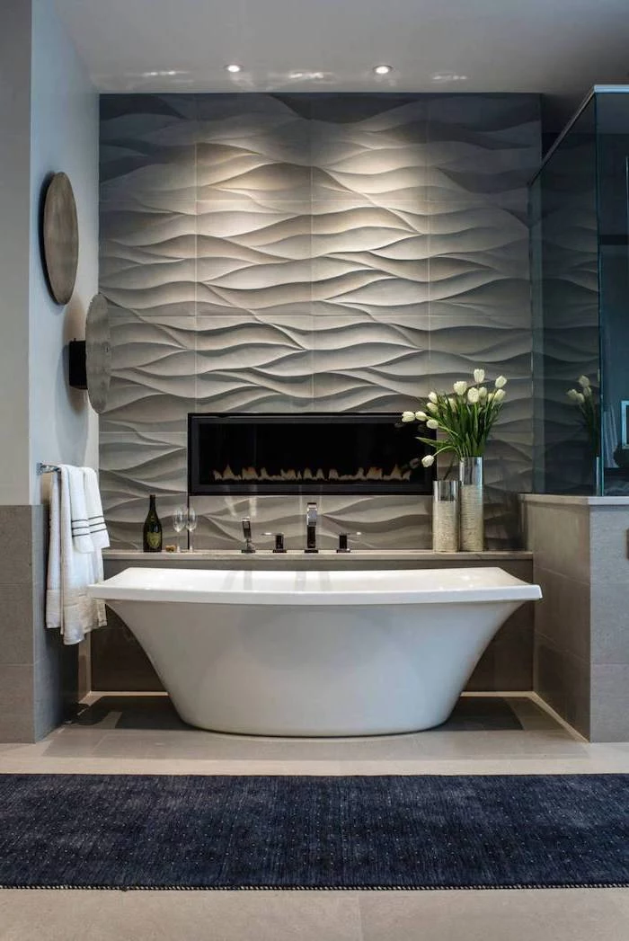 gray 3d tiles accent wall with fireplace behind the bathtub bathroom floor tiles beige tiles on the floor