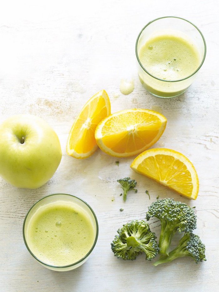 how to detox your body lemon slices apple and broccoli placed on white wooden surface two glasses with smoothie inside