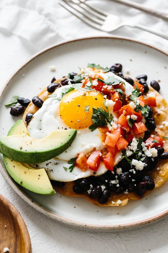 huevos rancheros with tomatoes black beans chopped parsley avocado slices on the side mexican dinner ideas