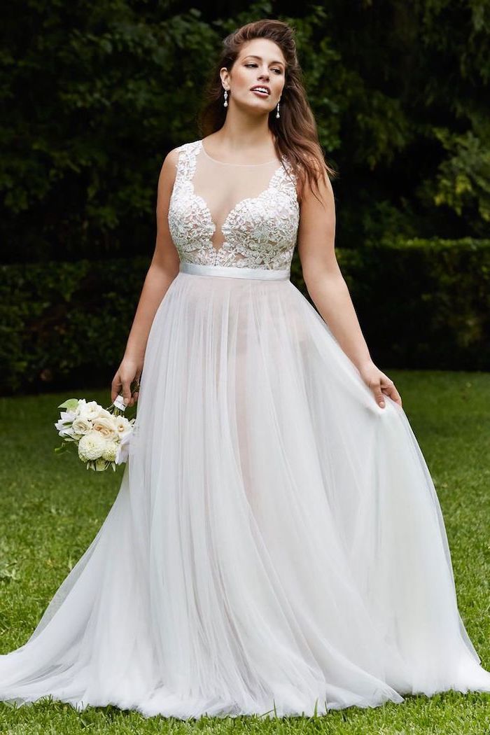 lace top with tulle bottom white boho wedding dress worn by brunette woman holding small white flower bouquet