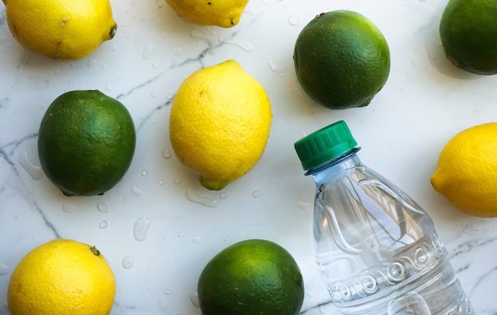 lemons and limes arranged on marble surface water bottle next to them best detox cleanse