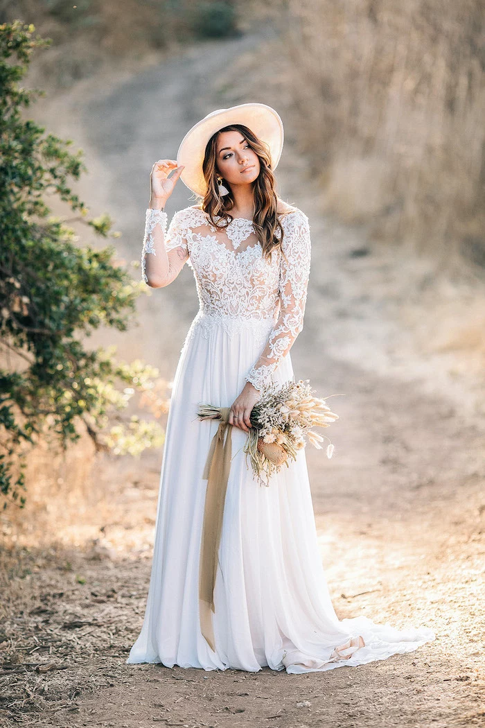 long sleeve boho wedding dresses woman with medium length wavy hair wearing dress with lacy top and lacy long sleeves bottom skirt made of tulle