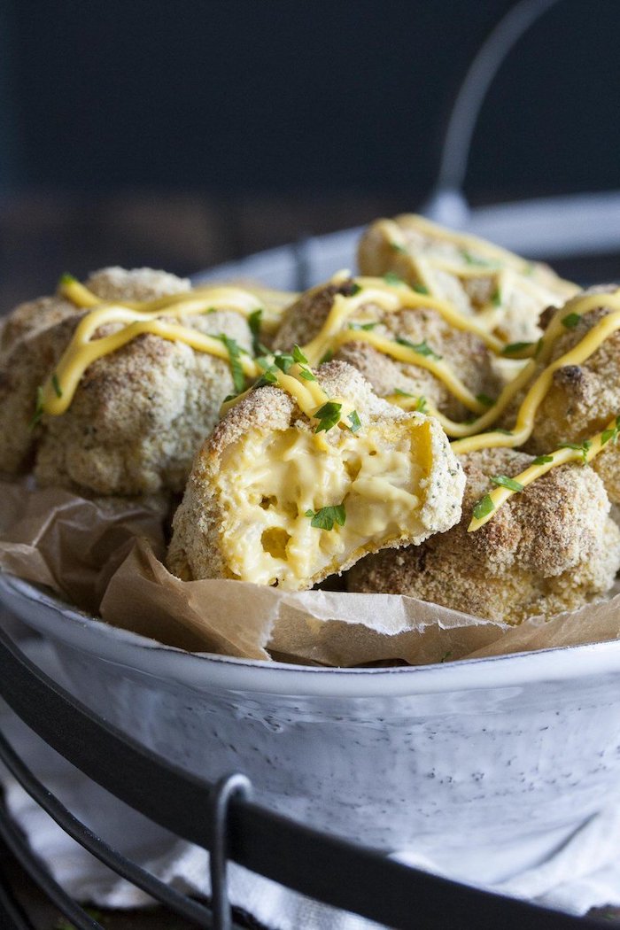 mac and cheese bites dipped in breadcrumbs vegan party snacks placed in paper lined ceramic bowl garnished with sauce