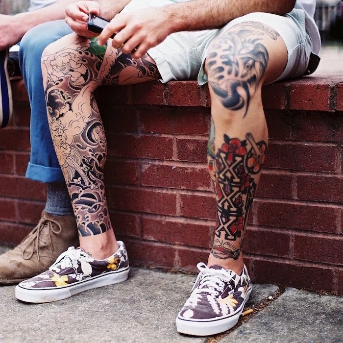 man sitting on small brick wall simple tattoos for men leg sleeves on both legs with colorful tattoos