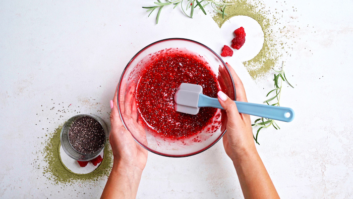 mashed raspberries with chia seeds added to it in glass bowl easy vegan appetizers placed on white surface