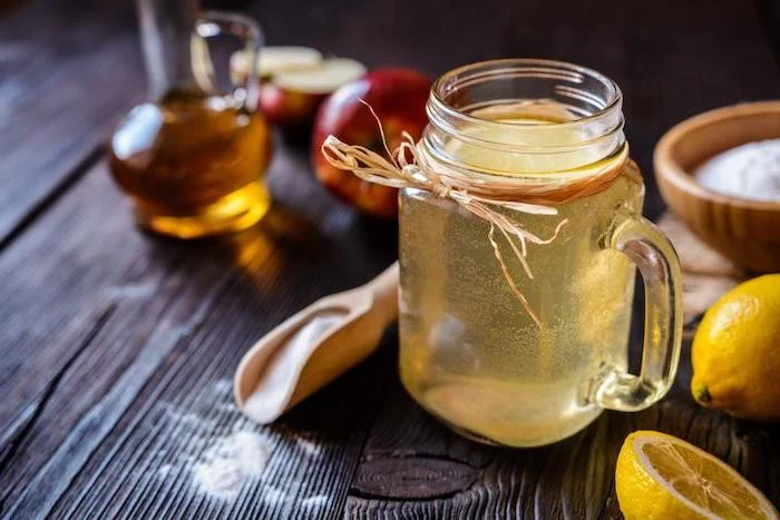 mason jar filled with apple cider vinegar and lemon juice how to detoxify your body placed on wooden surface