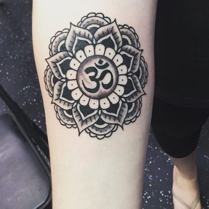 meaningful tattoos for women om symbol in the middle of mandala flour forearm tattoo on woman wearing black leggings