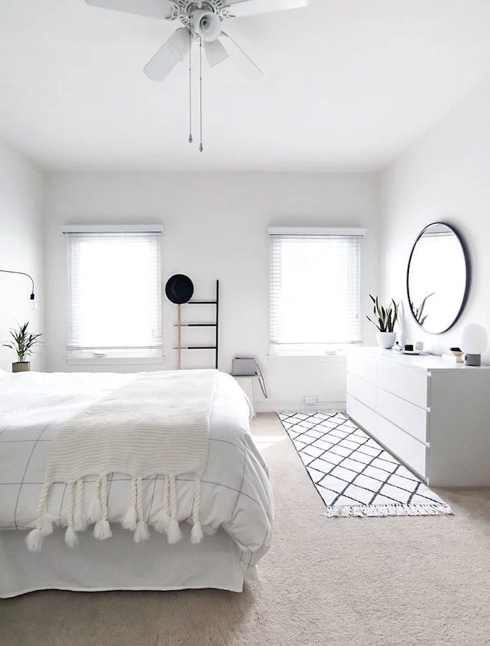 minimalistic bedroom in all white scandinavian design round mirror above a vanity white bed sheets