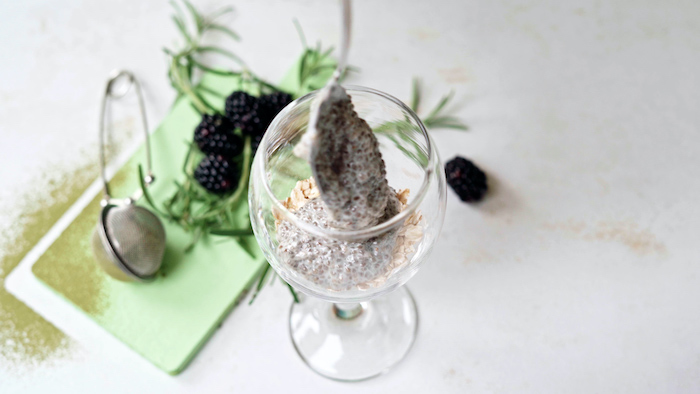 oats on the bottom of wine glass topped with chia seeds with milk vegan bites placed on white surface