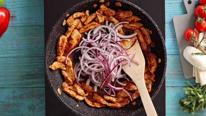 onion cooking in the middle of saucepan chicken on the sides traditional mexican food blue wooden surface