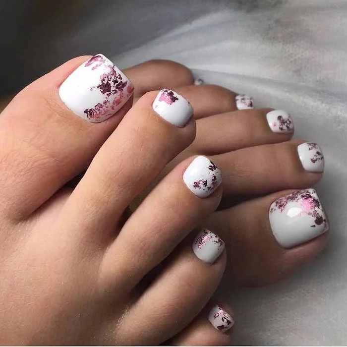 pink leaves on white nail polish cute acrylic nails pedicure in white legs placed on white fabric