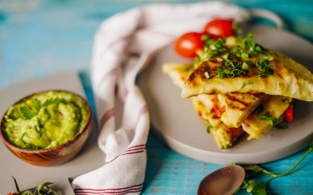 quesadilla arranged on gray plate garnished with chopped parsley traditional mexican food guacamole sauce on the side