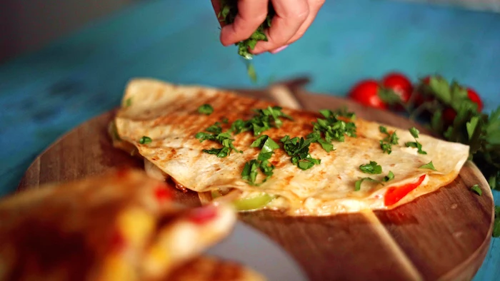 quesadilla placed on round wooden cutting board easy mexican dishes garnished with chopped parsley