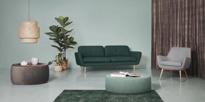 scandinavian design dark green sofa gray armchair light freen walls and floor two ottomans