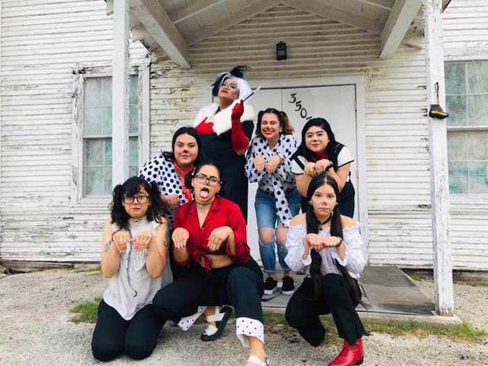 seven women dressed as cruella de ville and the dalmations halloween costumes for 3 people photographed in front of spooky house