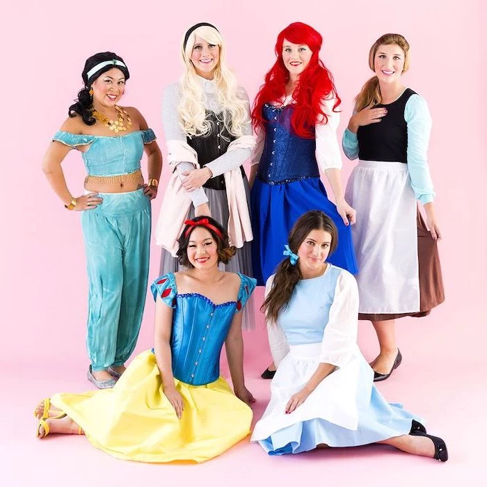 six women dressed as different disney princesses photographed in front of pink background group halloween costume ideas