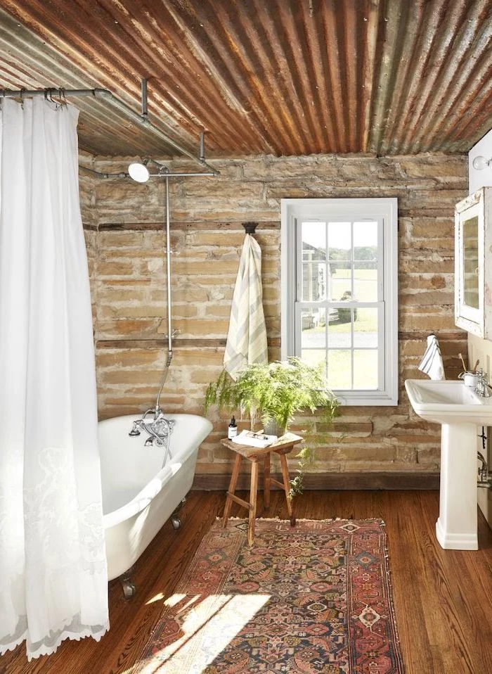 stone walls wooden floor with rug farmhouse bathroom tile white curtain around bath wooden table next to it