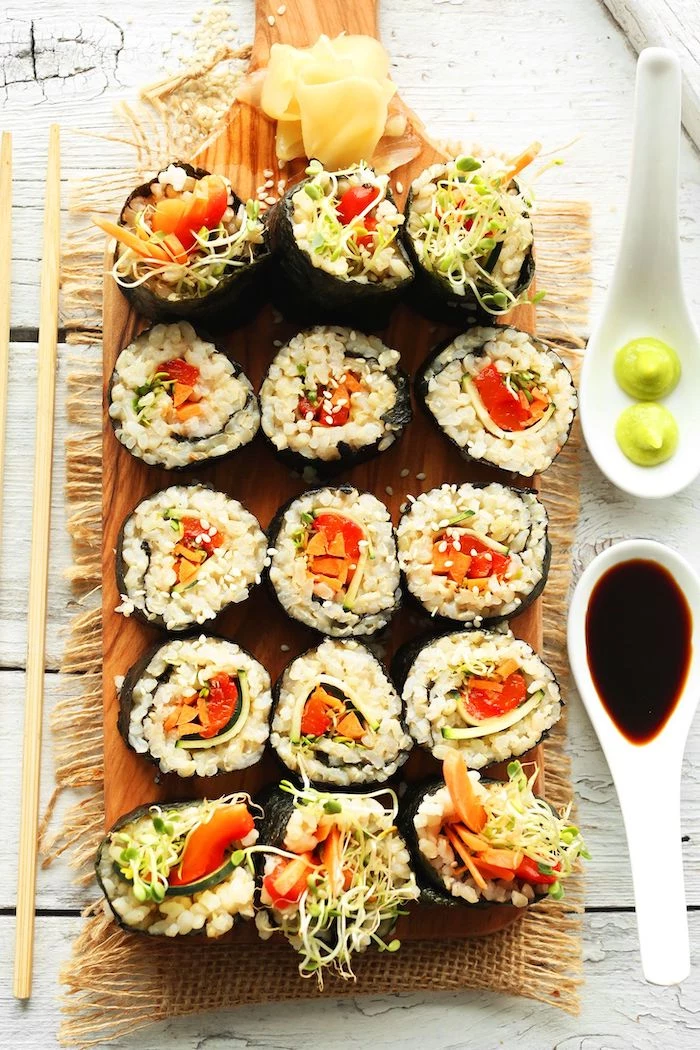 sushi with brown rice tomatoes carrots sprouts best vegan appetizers arranged on wooden cutting board
