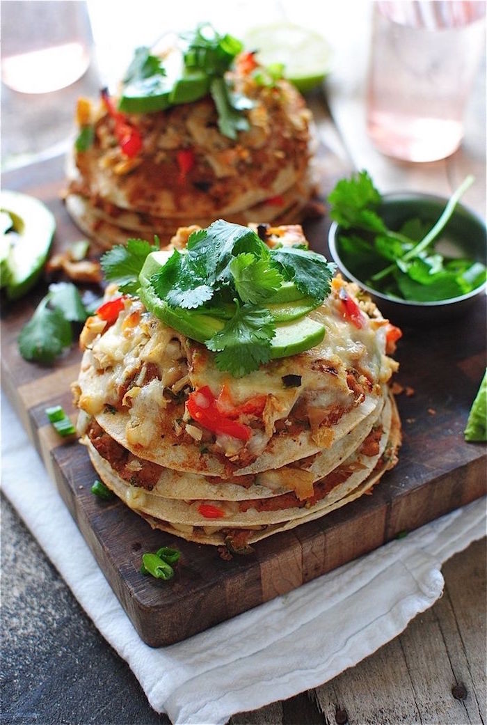 tacos placed on wooden cutting board mexican dishes garnished with avocado slices and fresh parsley