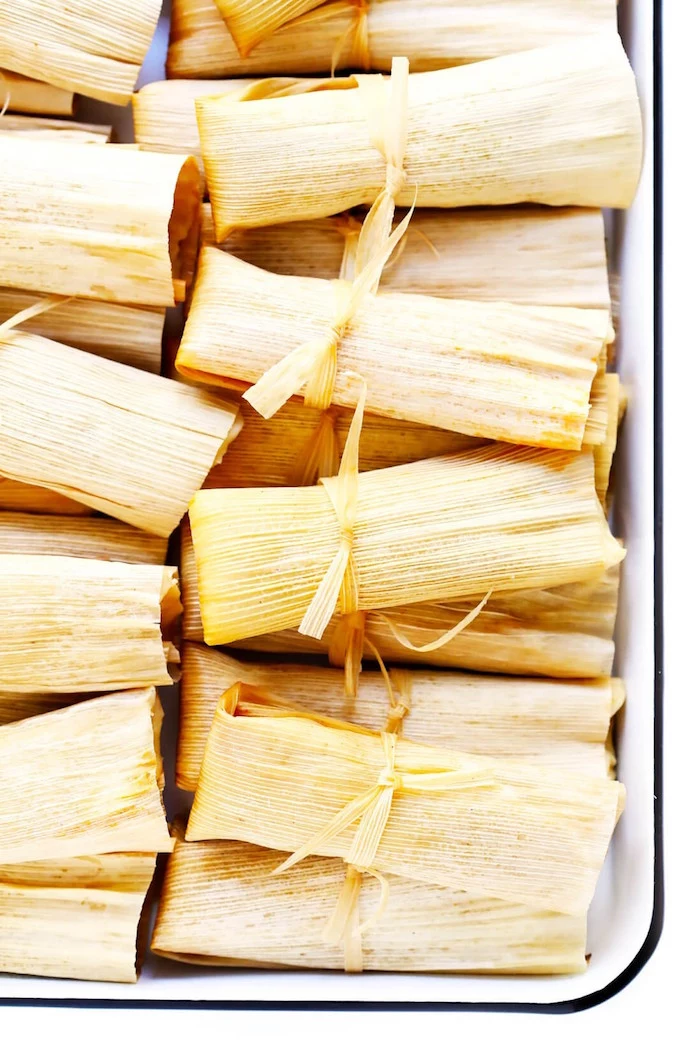 tamales wrapped in corn husk arranged in white baking sheet popular mexican food