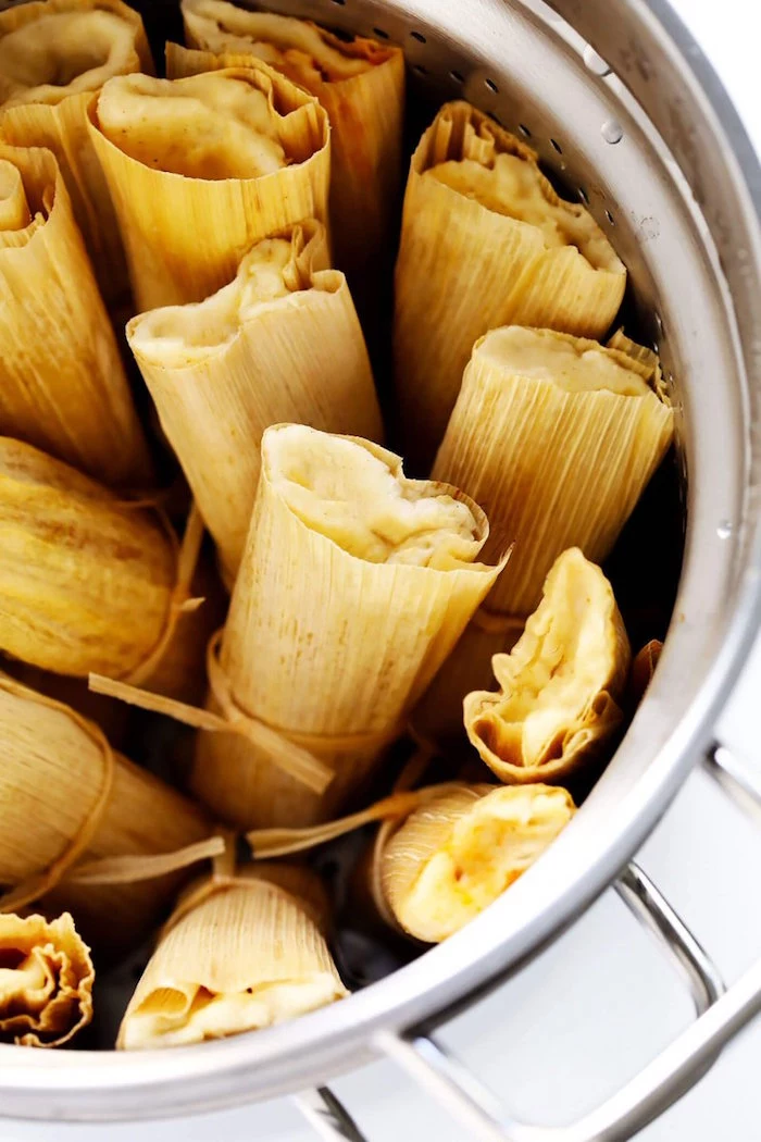 tamales wrapped in corn husk arranged inside silver pot best mexican dishes placed on white surface