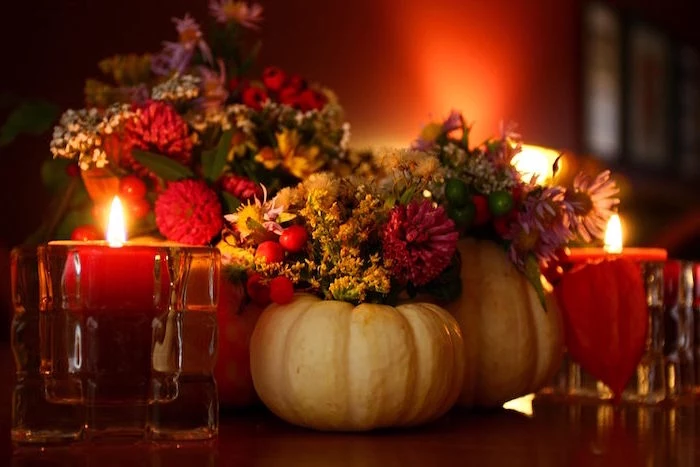 thanksgiving wallpaper table arrangement with carved out pumpkins with flowers in them surrounded by candles