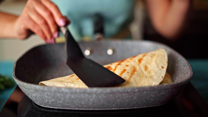 tortilla being folded with black spatula in gray grill pan easy mexican dishes