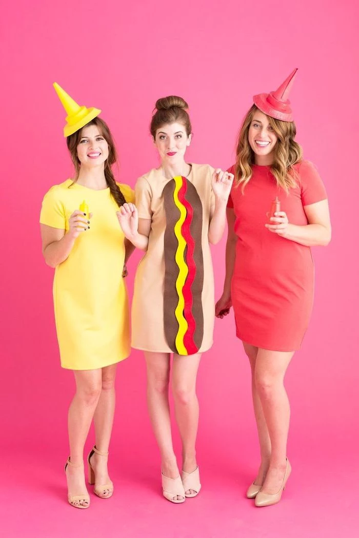 trio halloween costumes three women one dressed as bottle of mayo another as ketchup woman in the middle as hot dog