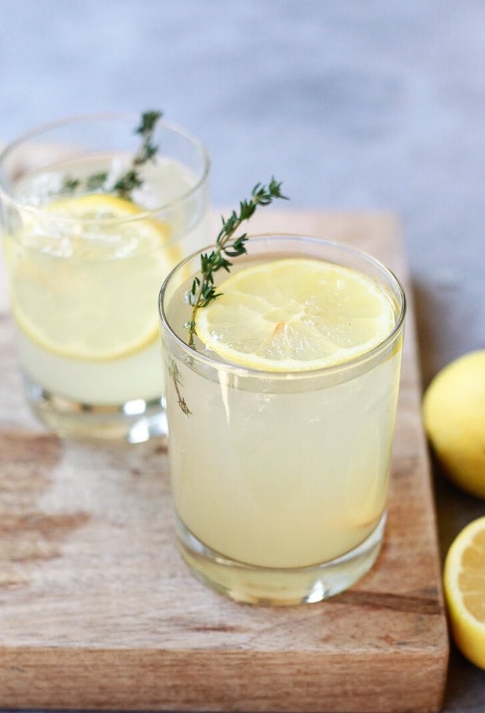 two glasses placed on wooden cutting board detox drinks for weight loss filled with apple cider vinegar lemon juice lemon slice
