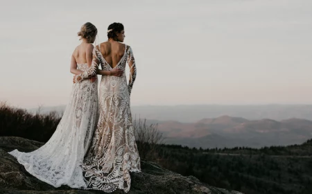 two women wearing all lace white dresses plus size beach wedding dresses photographed standing on a hill hugging