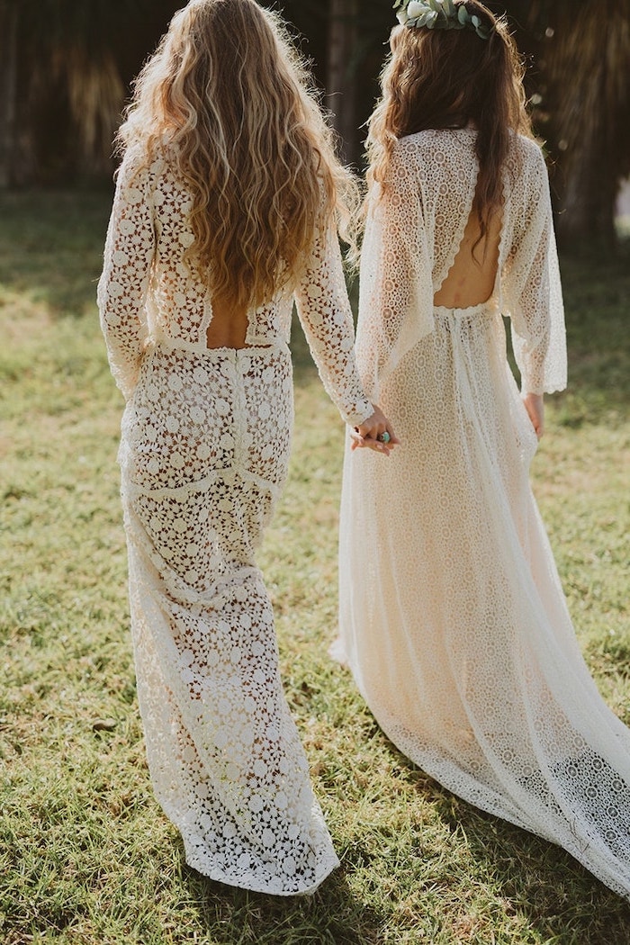 two women with long hair wearing all lace white long dresses holding hands boho beach wedding dress