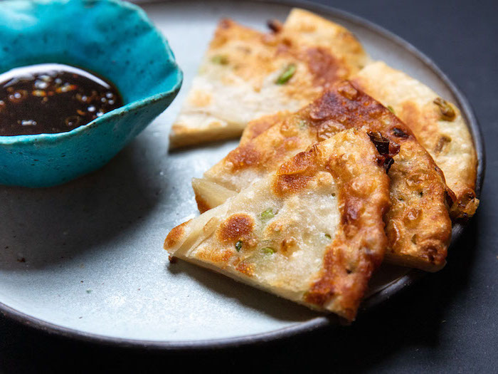 vegan appetizers baked pita bread with herbs arranged on gray plate with small blue bowl with dip on the side