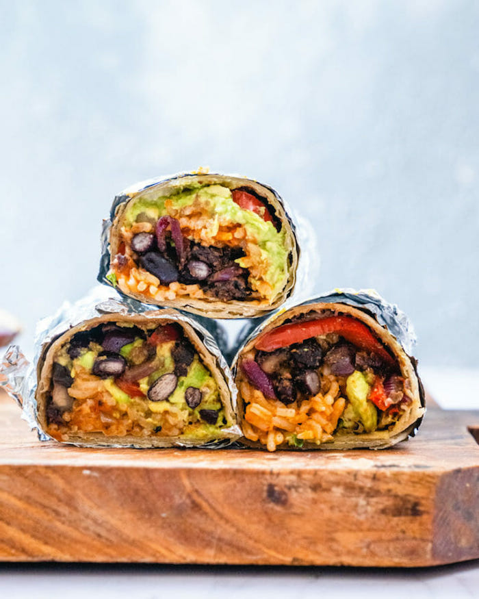 vegan burritos wrapped in foil popular mexican food arranged on wooden cutting board